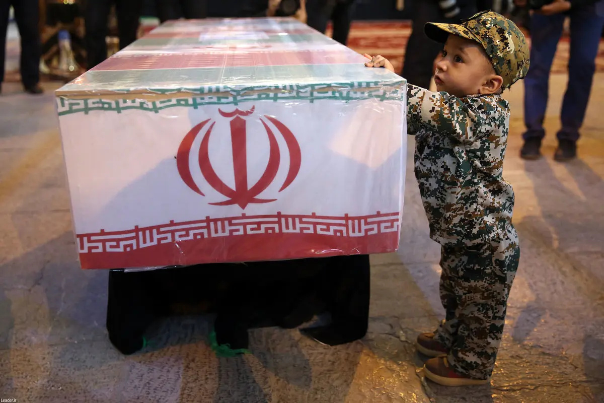 تصویری دردناک از فرزند شهید حججی در کنار تابوت پدر