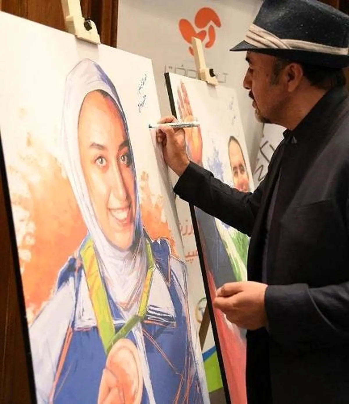 تصویری از رضا عطاران در حال امضای تابلوی کیمیا ایران