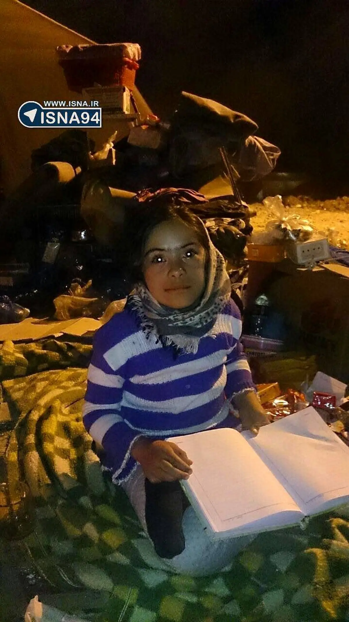 دختر کوچک زلزله‌زده‌ روی آوارها و در تاریکی درس می‌خواند/عکس